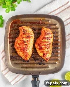 two cooked chicken breasts on a pan.