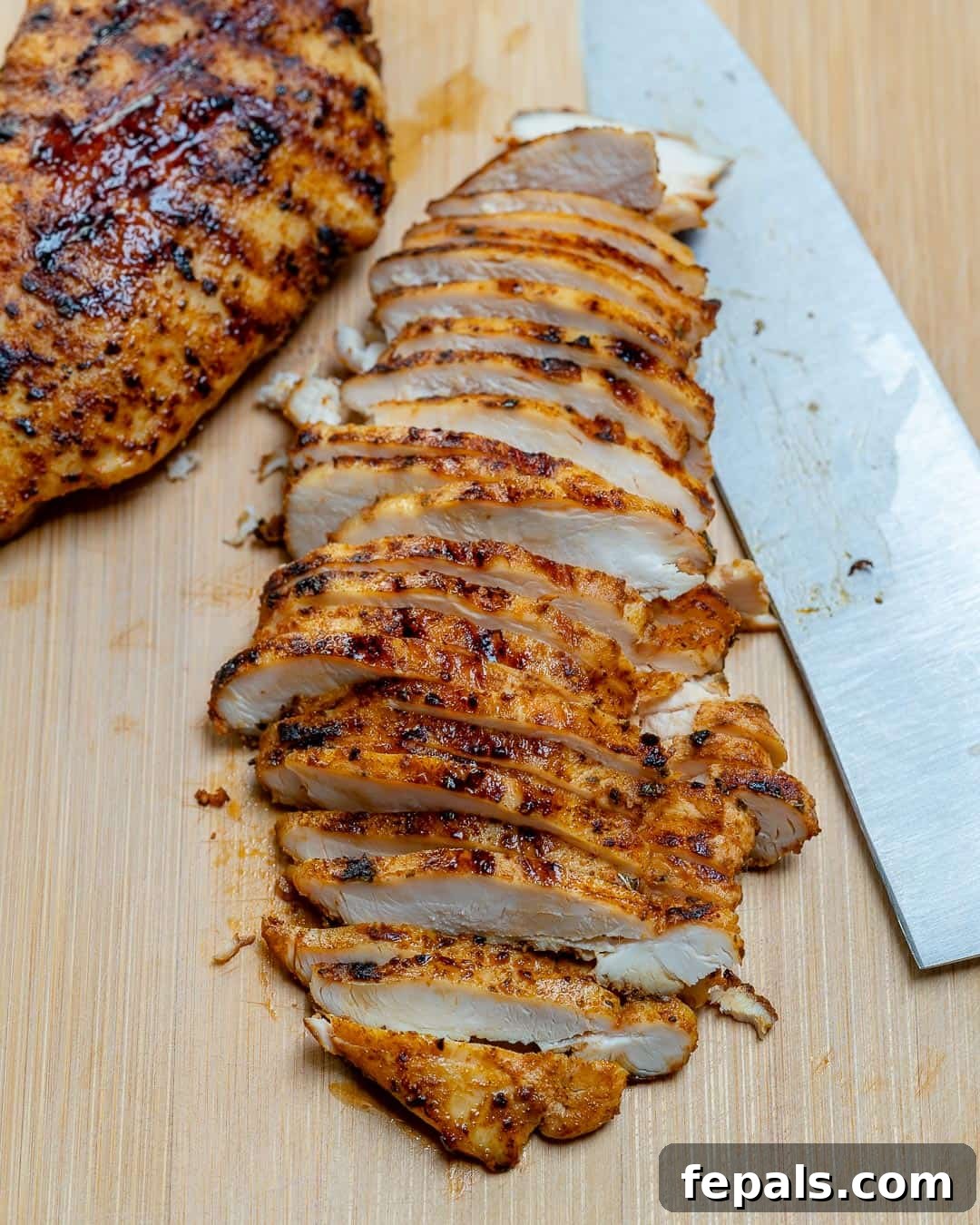 Fiesta Chicken Bowl 5 Sliced grilled chicken on a cutting board with a knife.