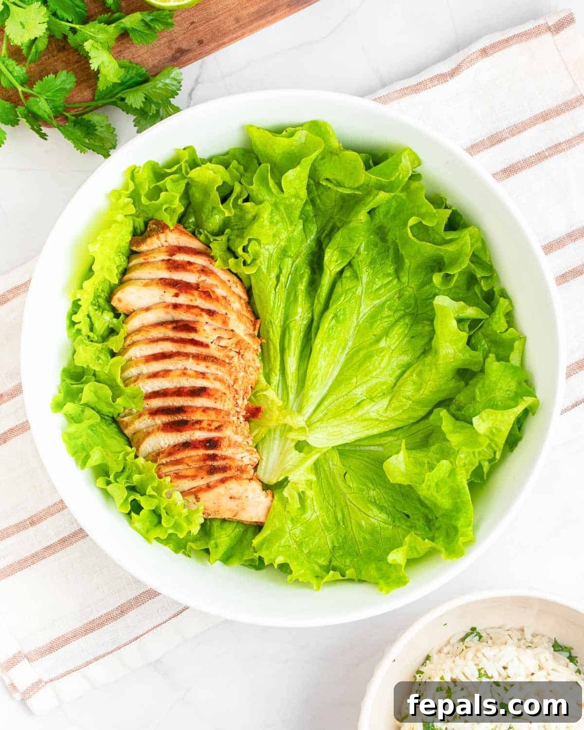Fiesta Chicken Bowl 7 Burrito bowl starting with lettuce and sliced chicken.