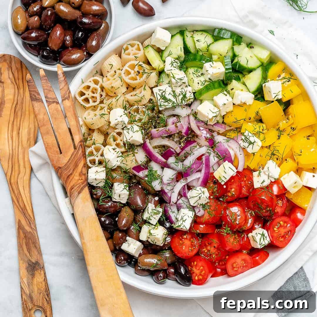 Zesty Greek Pasta Salad 4 A vibrant Greek pasta salad, filled with colorful vegetables and crumbled feta, served in a pristine white bowl.