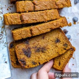 Hand holding a piece of Chocolate Chip Pumpkin Bread slice.