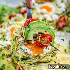 Hand holding a portion of baked zucchini and eggs over a dish.