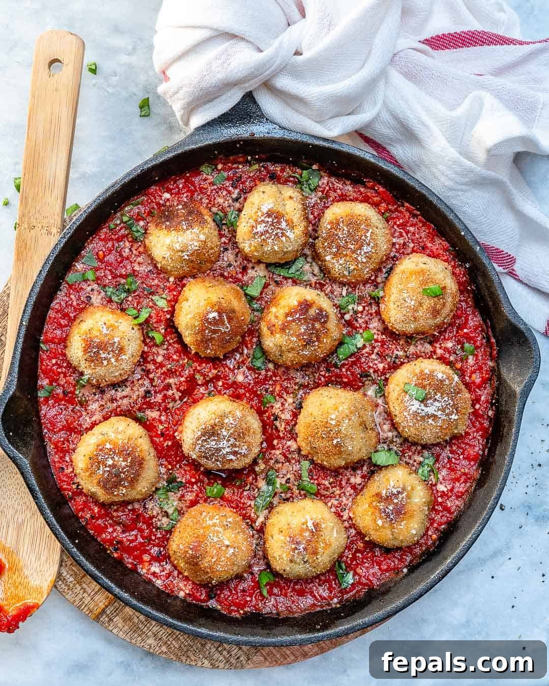 Cheesy Chicken Parmesan Meatballs in Garlic Tomato Sauce Top view of delicious cheesy chicken parmesan meatballs simmering in a rich garlic tomato sauce in a skillet, garnished with fresh basil.