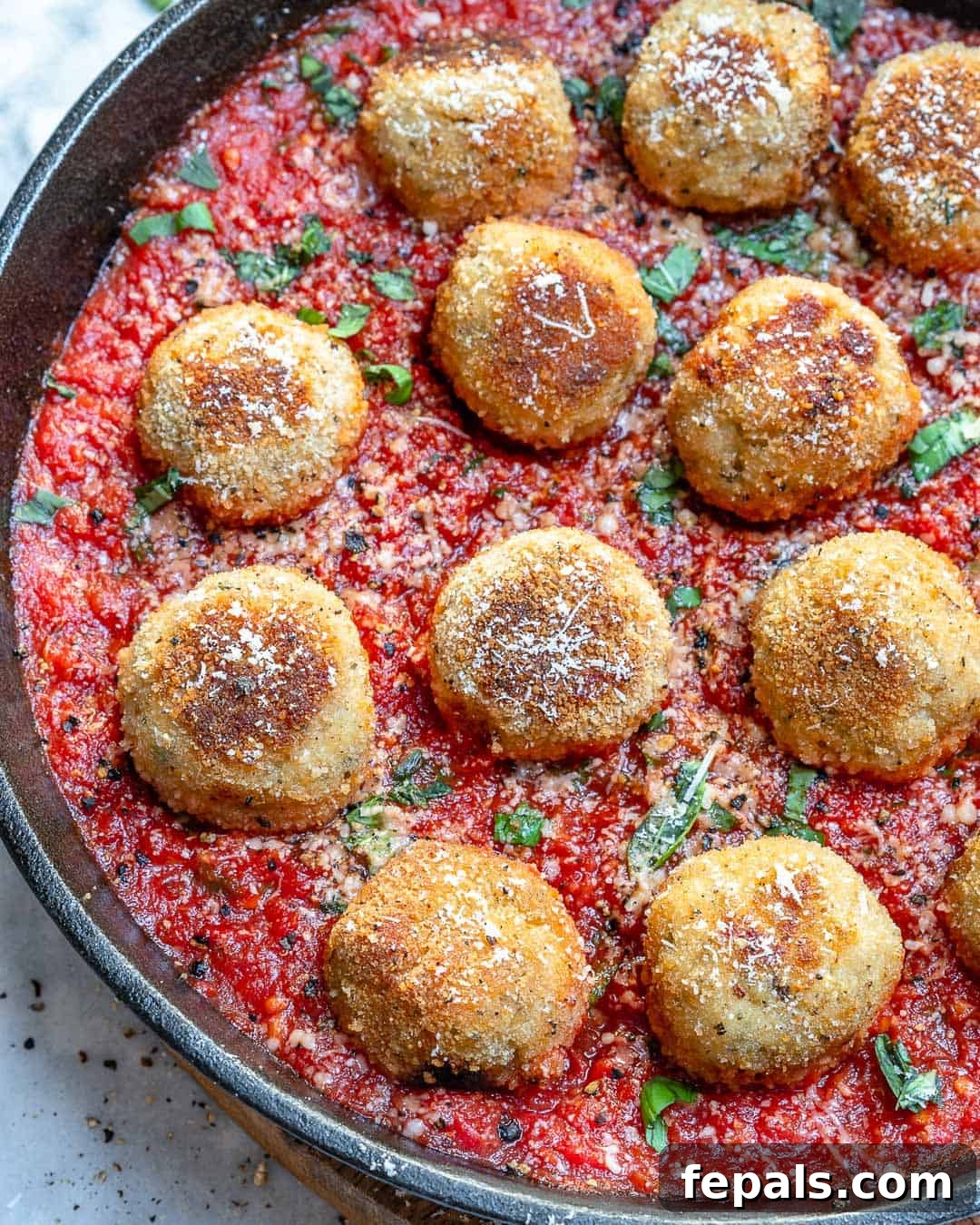 Healthy Chicken Parmesan Meatballs Simmered in Tomato Sauce Close-up of golden-brown chicken parmesan meatballs covered in a rich tomato sauce, ready to be served.