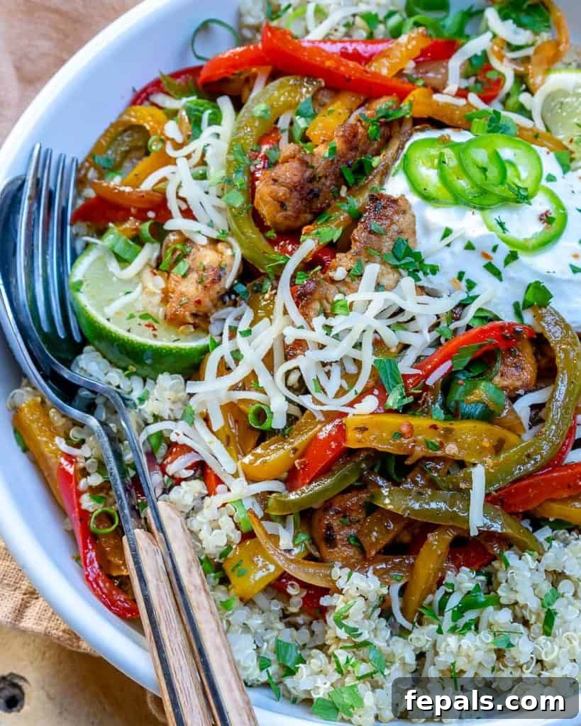Close-up of a fork and spoon ready to dive into a vibrant bowl of chicken fajita mix with vegetables.