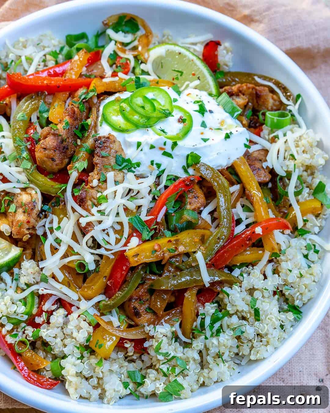 Top-down shot of a beautifully arranged bowl of easy chicken fajitas with colorful vegetables and toppings.