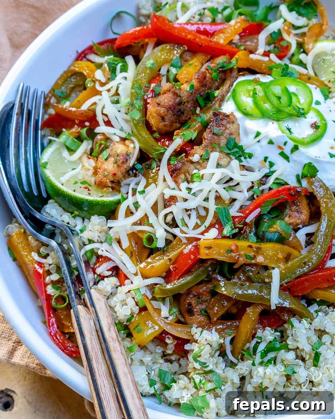 A fork and spoon in a bowl of chicken fajita mix, illustrating the delicious texture and ingredients.