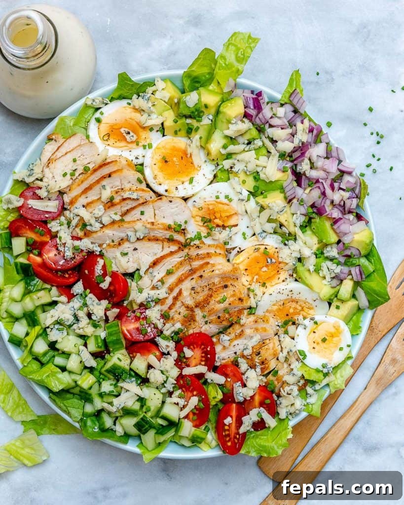 top view of a bowl of chicken cobb salad with a jar of dressing next to it