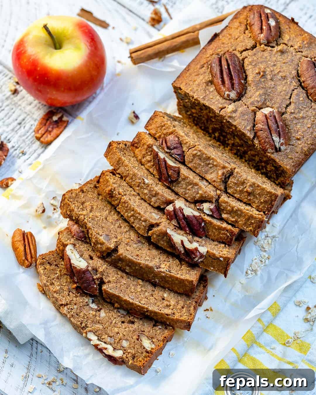 A baked apple bread loaf, with half of it sliced and the slices stacked beautifully.