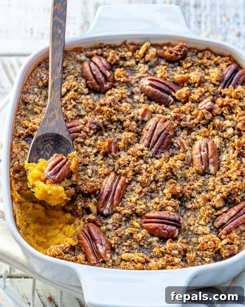 side shot of a white dish with Butternut squash  topped with a layer of sugar pecan with wooden spoon in dish
