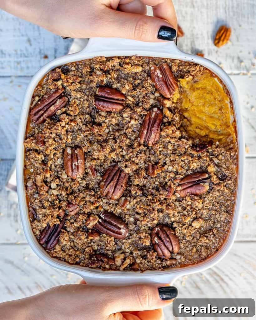 top view Butternut squash casserole with hand holding the white dish 