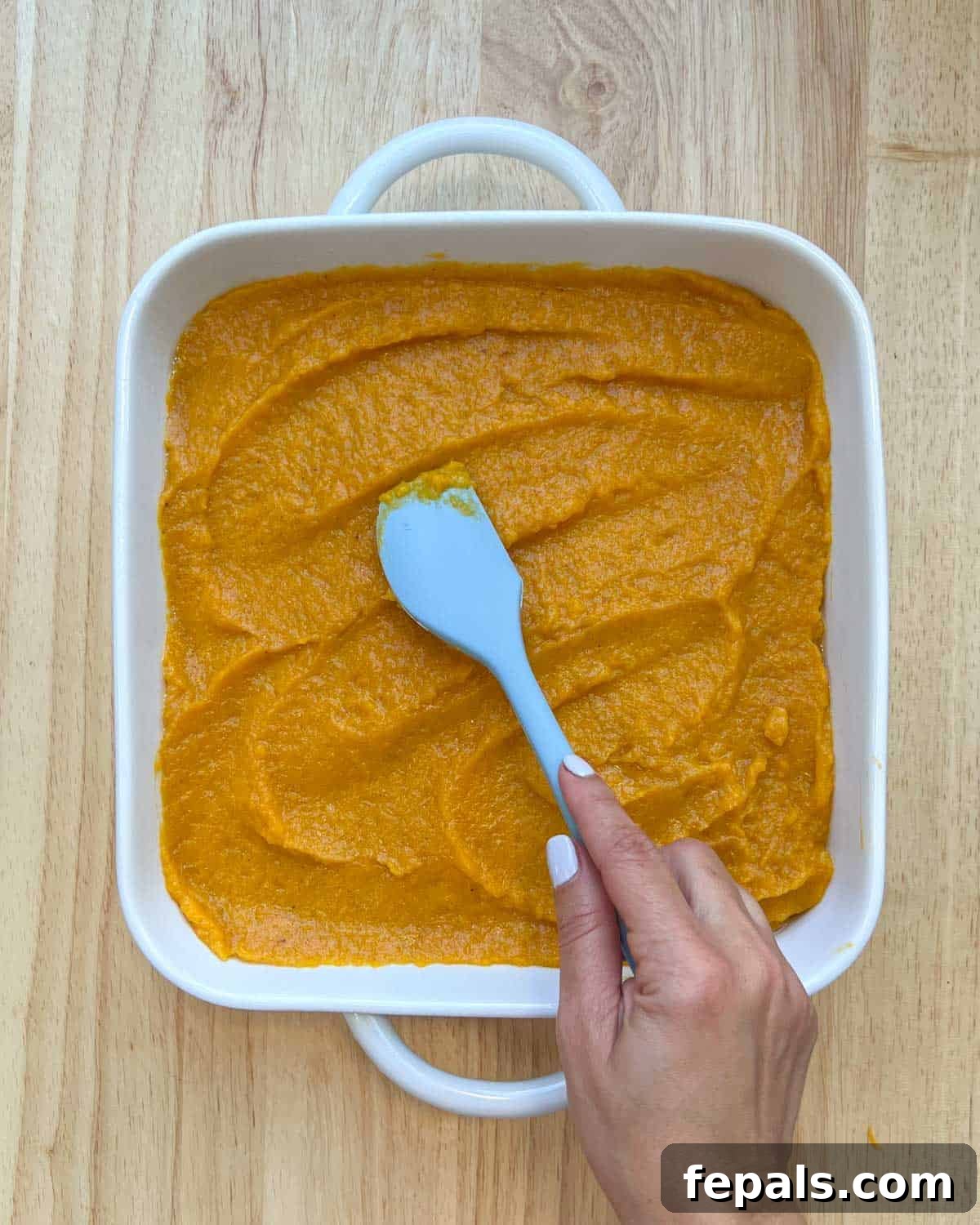 Butternut squash puree base added to a baking dish and spread out evenly with a spatula.