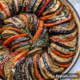 top close up view of slices of zucchini, eggplants and tomatoes stacked next to each other