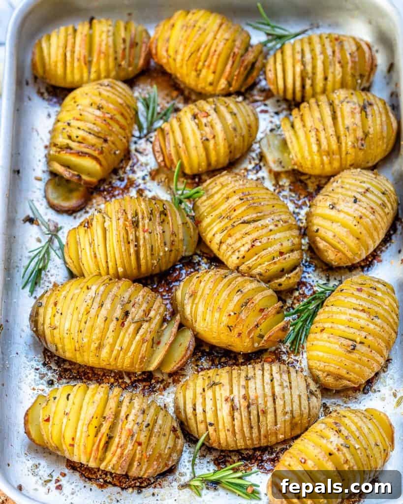 Golden Accordion Potatoes 8 top view of baked sliced potatoes on a sheet pan with rosemary garnish