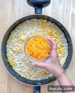 Velvety One-Pot Cheesy Corn 15 shredded cheddar cheese being added over cheesy corn.