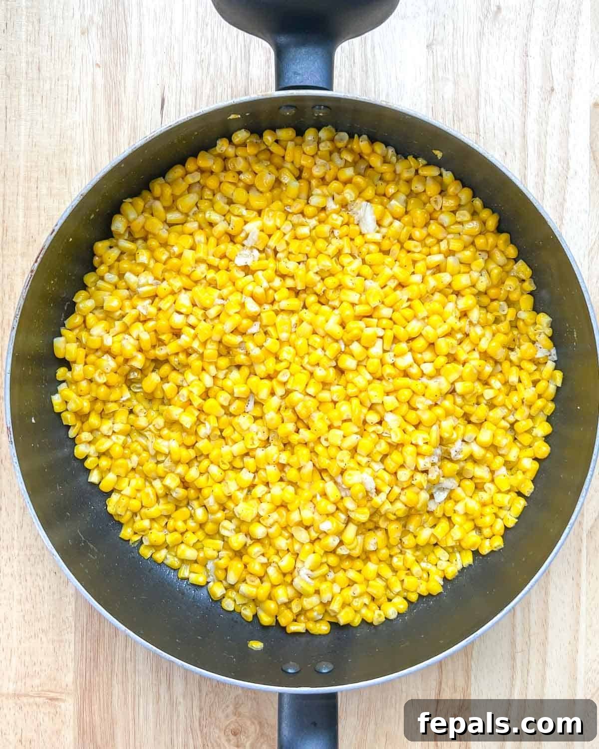 Velvety One-Pot Cheesy Corn 5 Corn and garlic gently searing and browning in a pan, releasing their aromatic flavors.