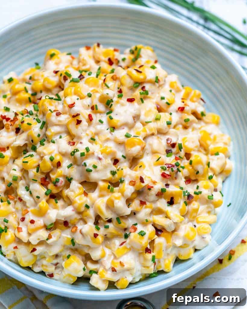 Velvety One-Pot Cheesy Corn 9 A beautiful side shot of a white plate generously filled with cheesy creamed corn, garnished with a sprinkle of chili flakes, ready to be enjoyed.