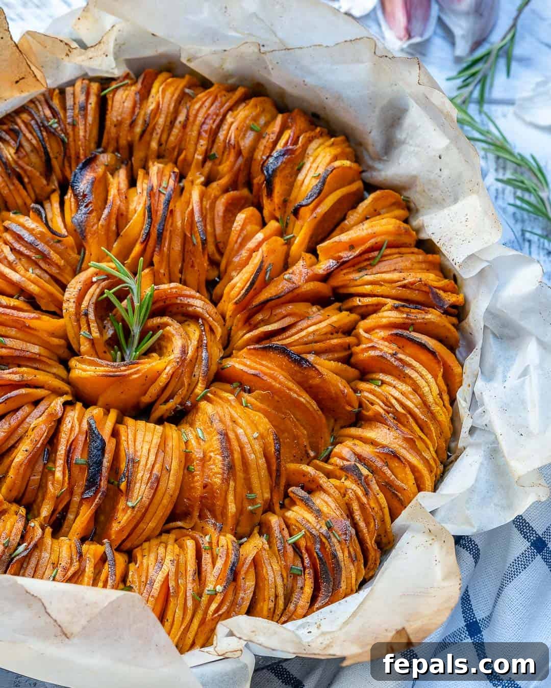 roasted sliced sweet potatoes stacked next to each other in a pan. 