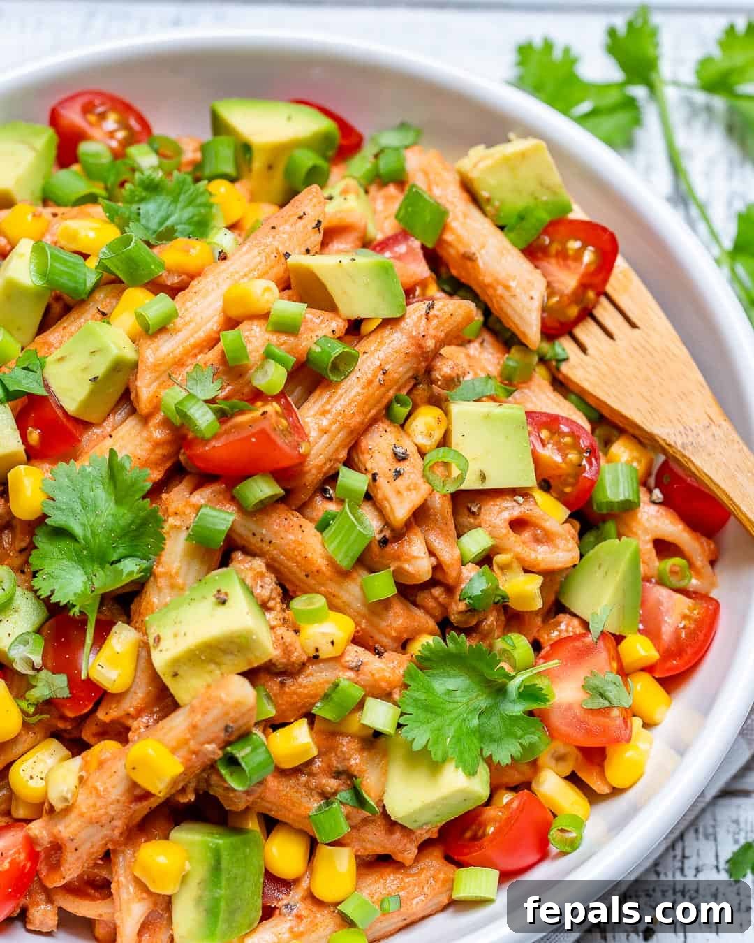 Fiesta Taco Pasta Salad 2 Delicious and creamy Taco Pasta Salad served in a bowl, garnished with fresh avocado and cilantro.