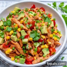Fiesta Taco Pasta Salad 8 round white plate with taco pasta salad topped with chopped avocado