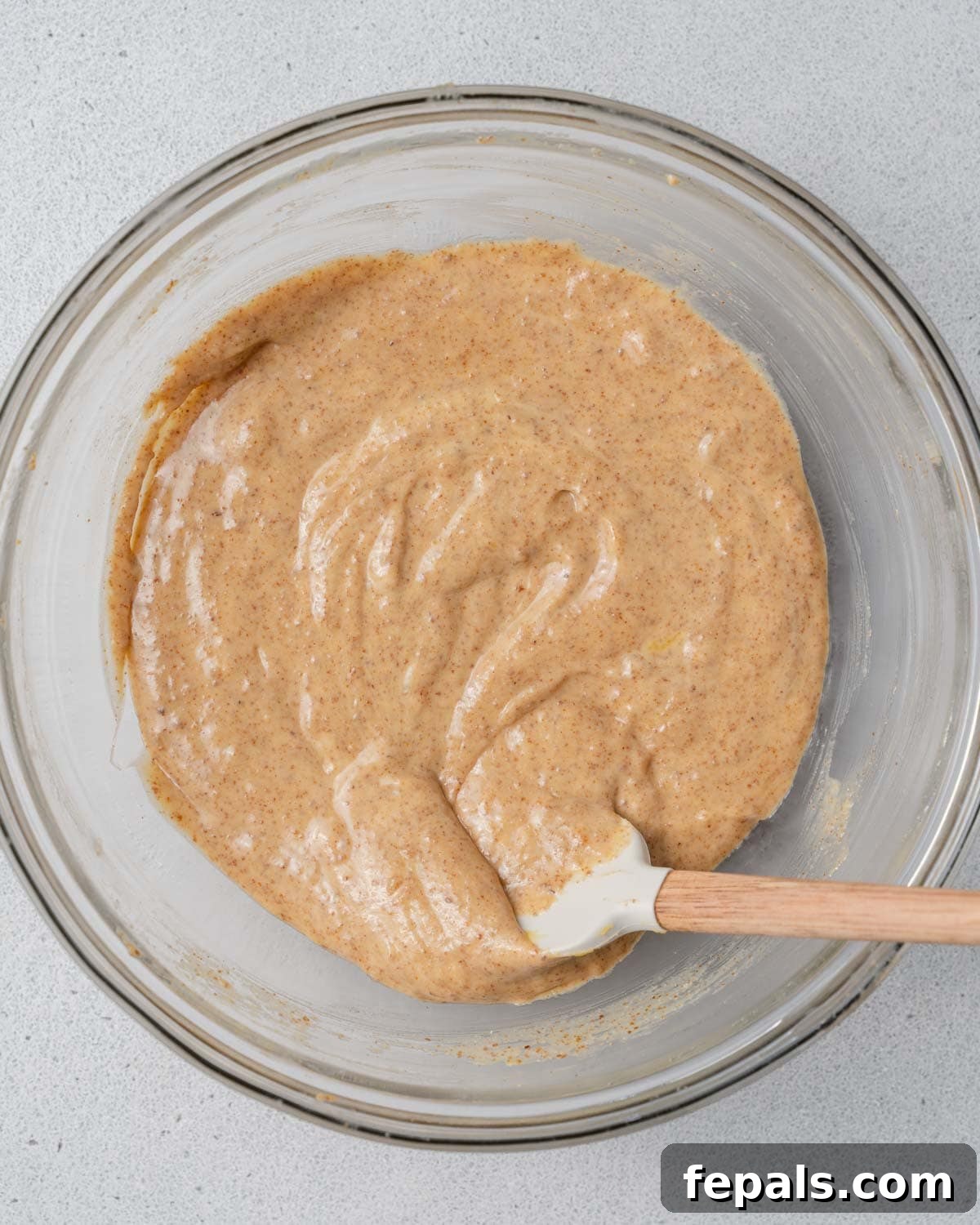 A bowl containing a smoothly mixed blend of almond butter, egg, and pumpkin puree.
