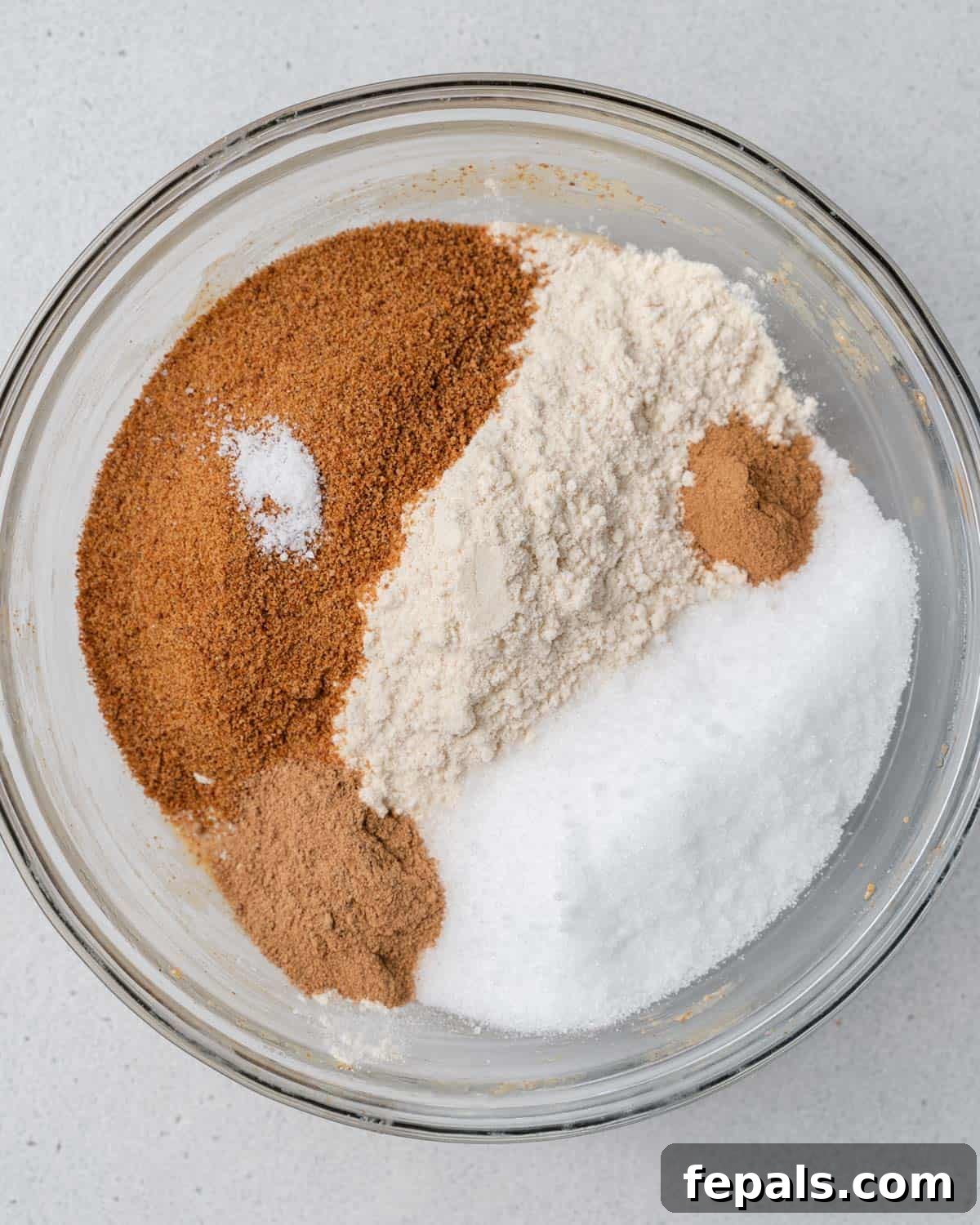 Dry ingredients including almond flour, coconut sugar, and spices are being stirred into a bowl.