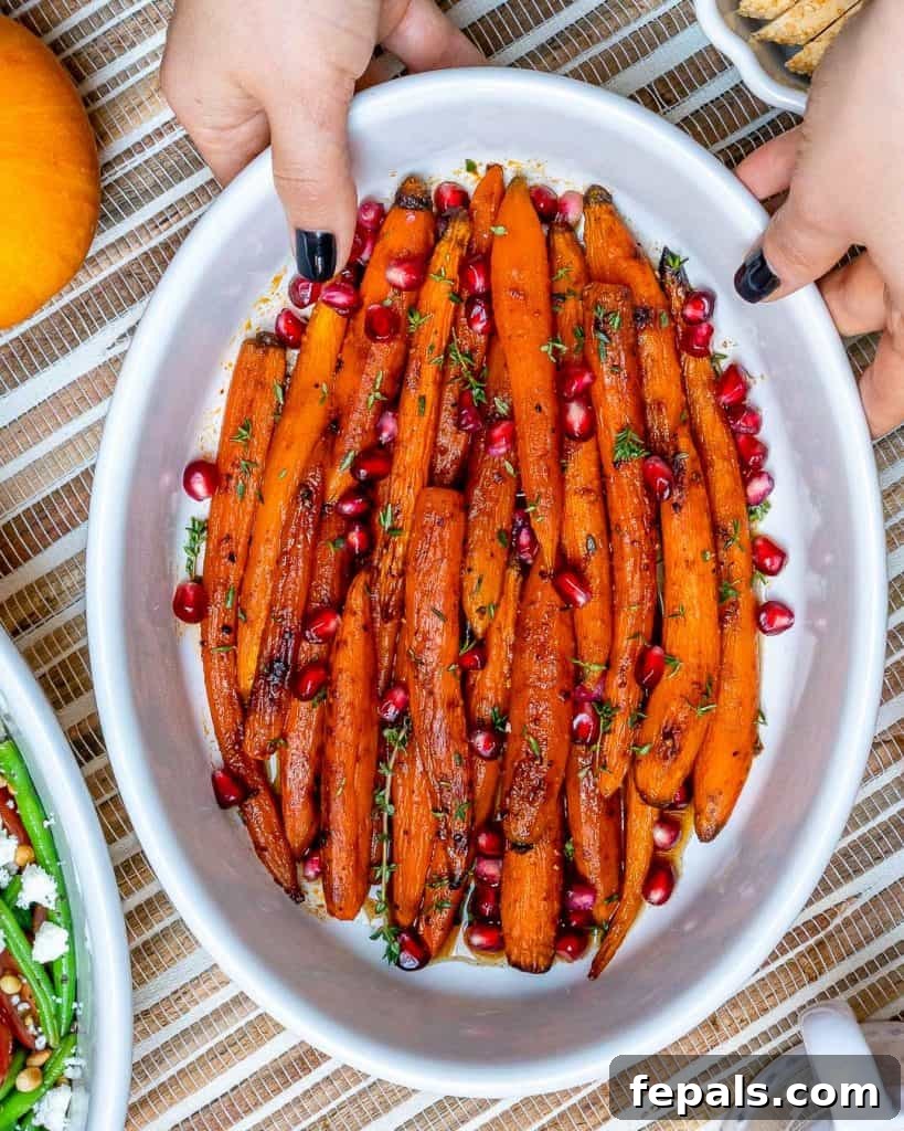 Roasted Carrots in a white dish with hand holding the dish