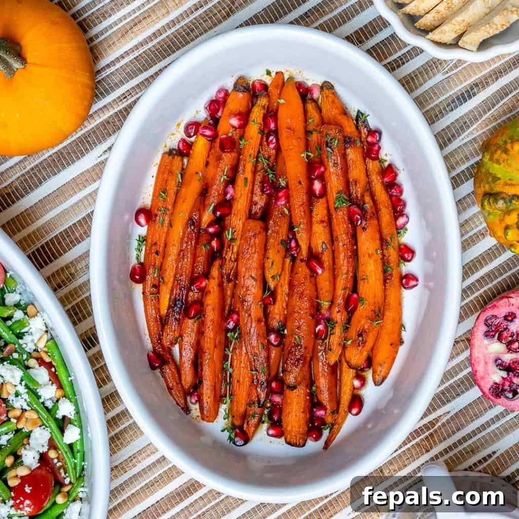top view of maple roasted carrots topped with pomegranate in a white dish