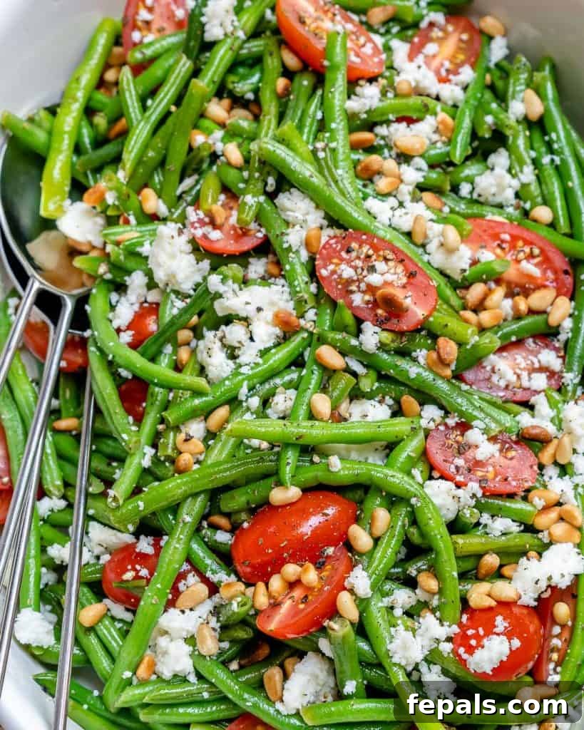 Sun-Kissed Tomato and Crisp Green Bean Salad 6 A close-up top view of a white bowl filled with green bean salad, showcasing the texture of the beans, the juicy cherry tomatoes, and the creamy feta cheese.