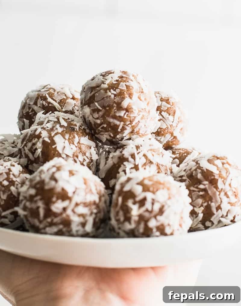Side view of a hand holding several date energy bites on a plate, ready to be enjoyed.