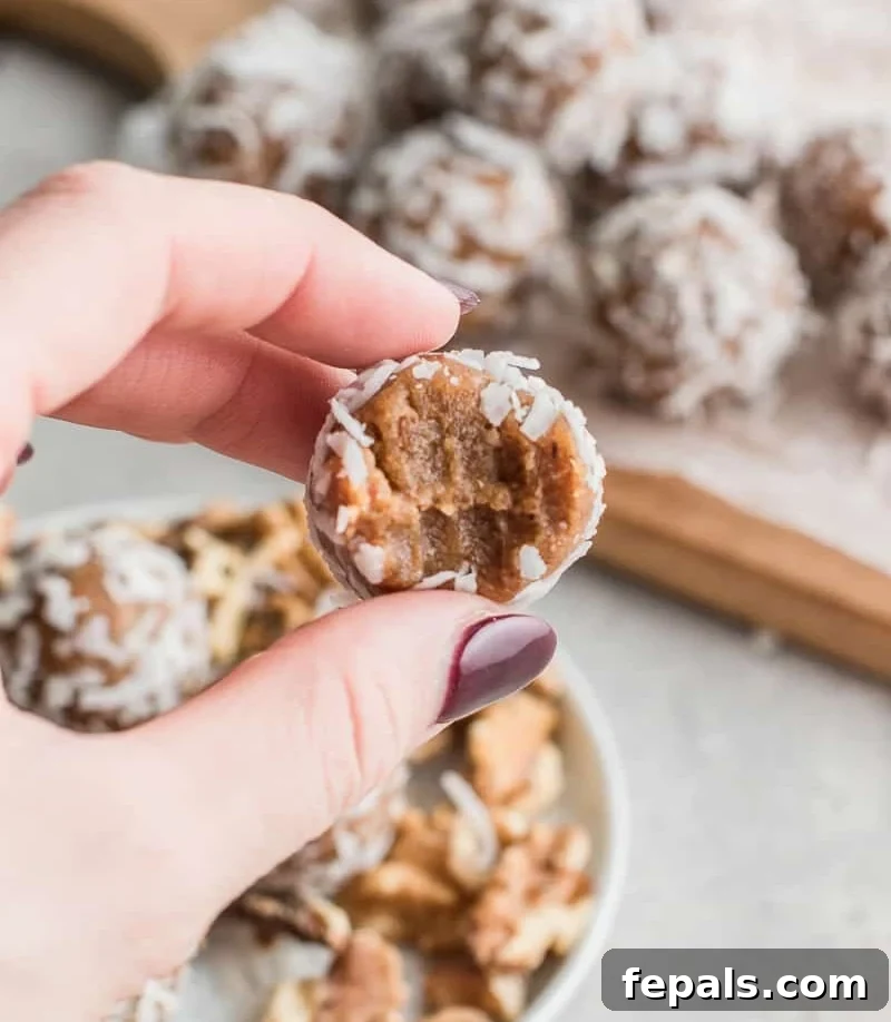 Hand holding a single, perfectly rolled date energy bite, showcasing its delicious appeal.