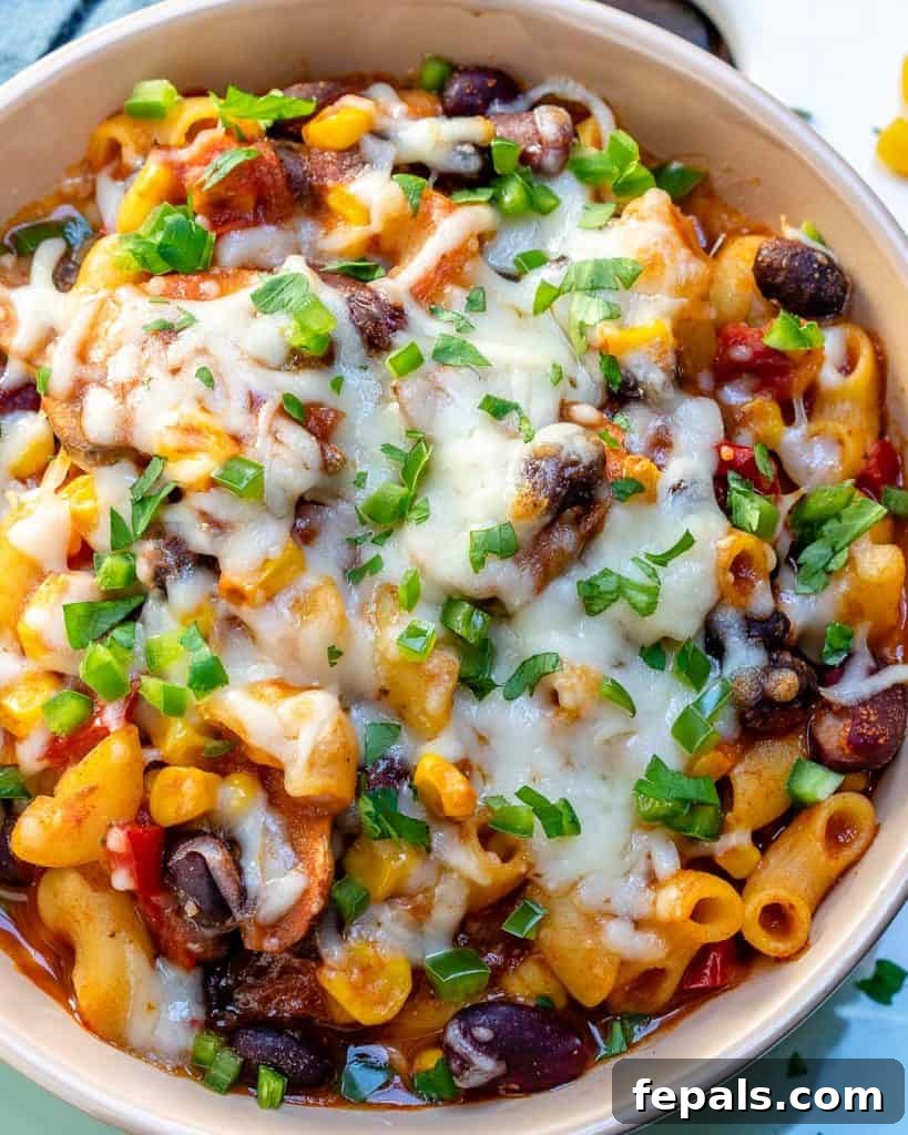 A white bowl of macaroni recipe with chili topped with fresh sliced green onions, showcasing a vibrant and appealing dish ready to be enjoyed.
