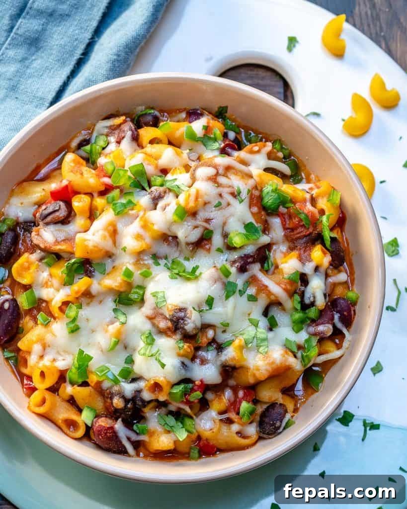 A top-down view of macaroni prepared with a rich chili sauce and beans, garnished with fresh green onions, highlighting its appetizing texture and vibrant colors.