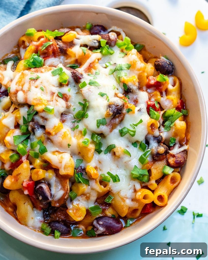 A top-down, close-up view of a bowl of macaroni recipe generously topped with chili and melted cheese, emphasizing its rich texture.