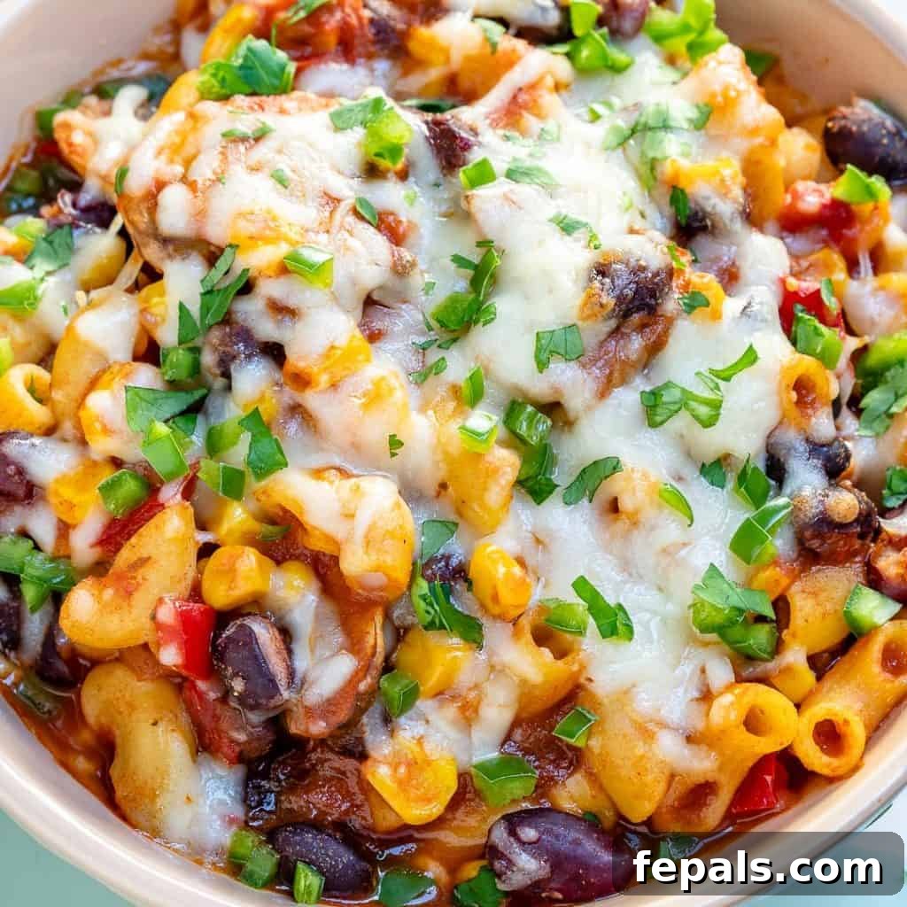 A close-up view of a bowl of chili macaroni generously topped with melted cheese and vibrant green onions, showcasing a delicious and comforting meal.