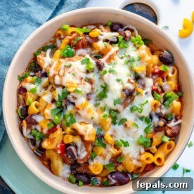 Top view of a round bowl of mac and cheese chili recipe topped with melted cheese, ready to serve.