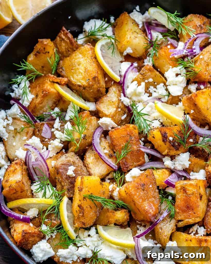 Zesty Greek Roasted Potatoes 6 close up view of crispy potatoes in a skillet with dill and crumbled feta cheese garnishes