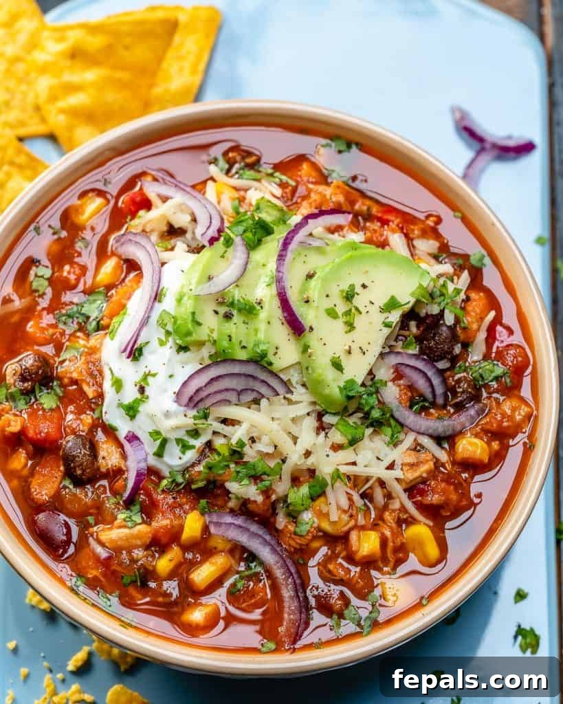 Ultimate Chicken Chili 7 top view of a bowl of chili topped with sliced avocado and sour cream