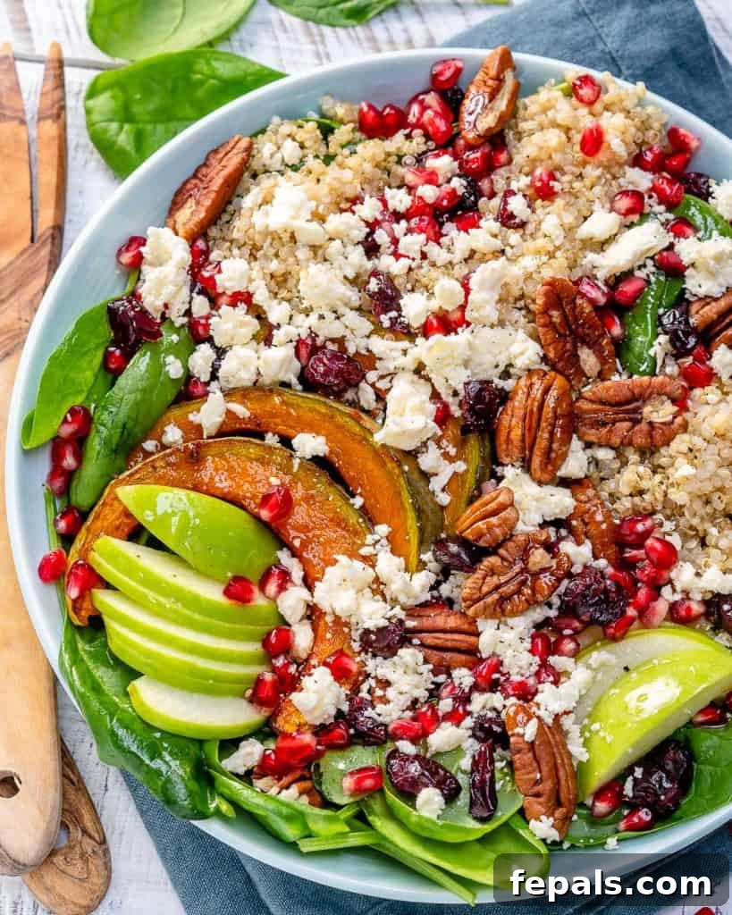 top view image of a loaded harvest quinoa salad in a white bowl with a wooden spoon on the left side