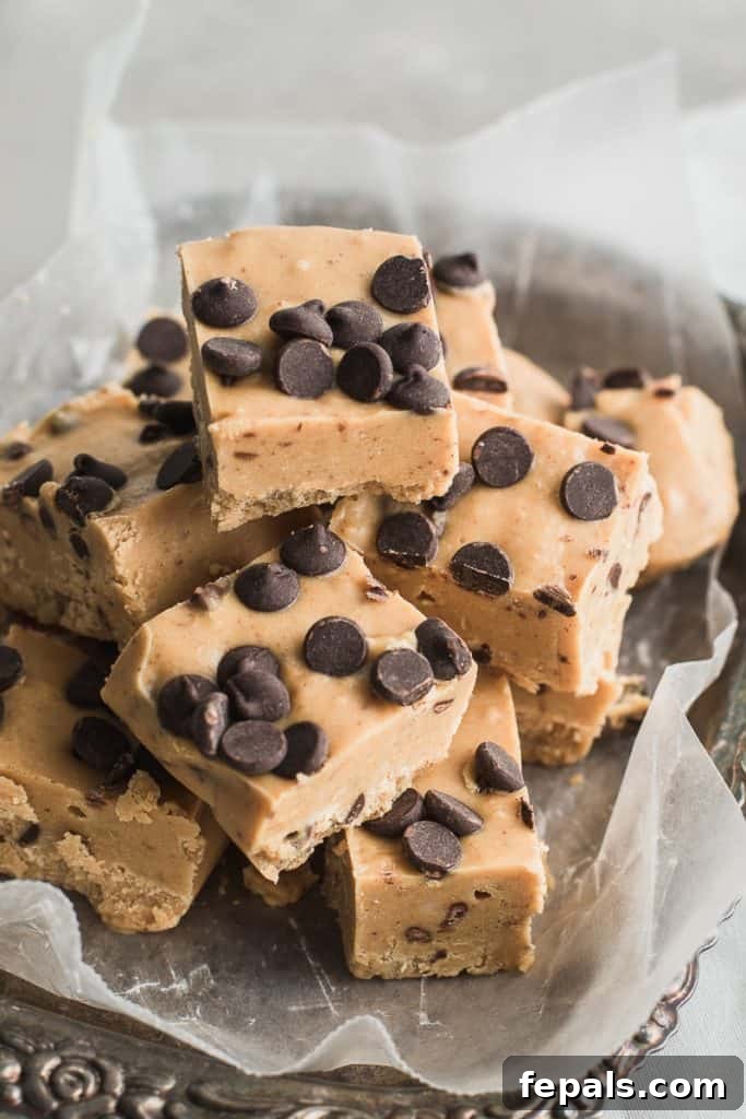 Effortless Chocolate Chip Cookie Dough Fudge 2 Decadent cookie dough fudge squares arranged on a plate with parchment paper, highlighting their creamy texture and chocolate chips.