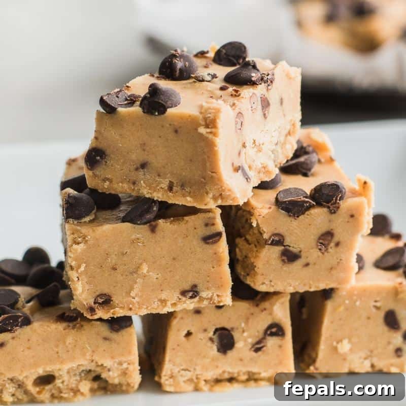 Effortless Chocolate Chip Cookie Dough Fudge 7 A charming pile of cookie dough fudge squares resting on a clean white surface, ready to be enjoyed.
