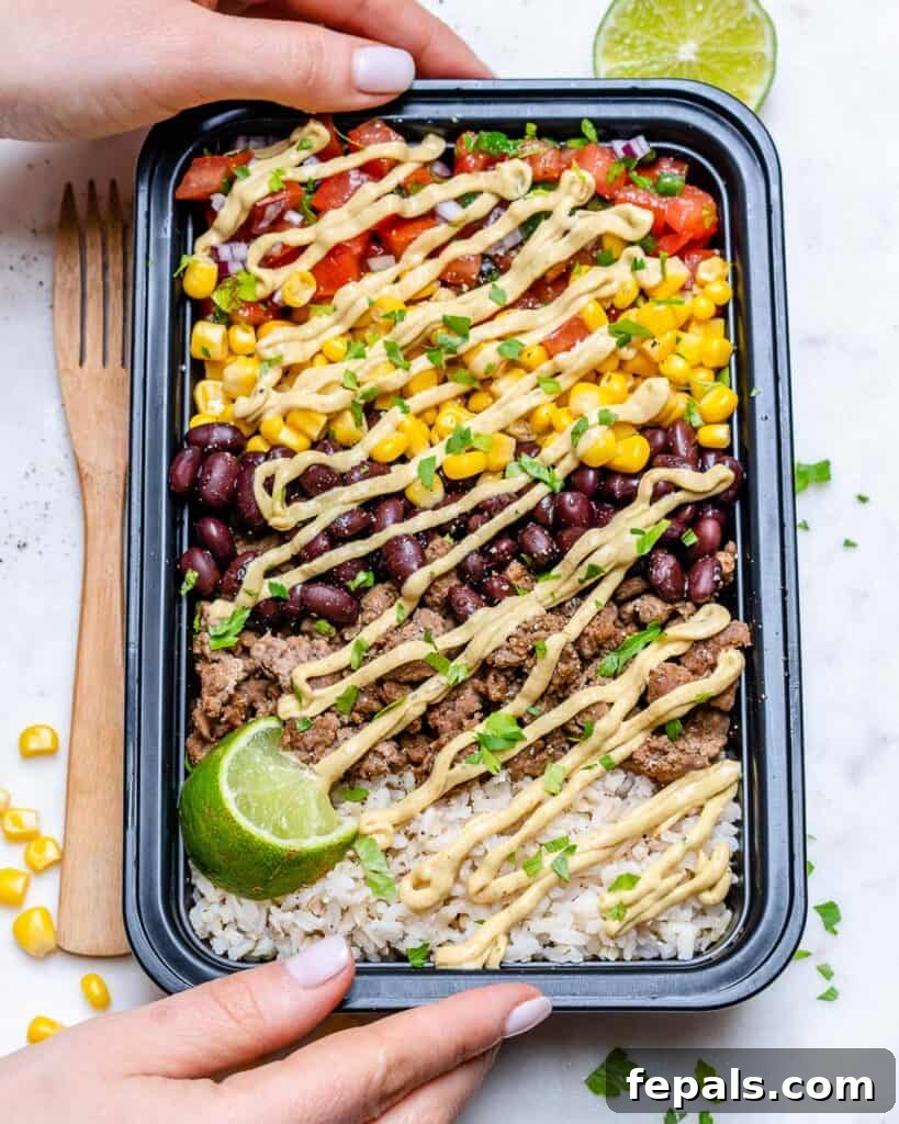 Beef Burrito Power Bowls 2 hand holding a black meal prep bowl with a beef burrito bowl with rice beans corn pico and ground beef