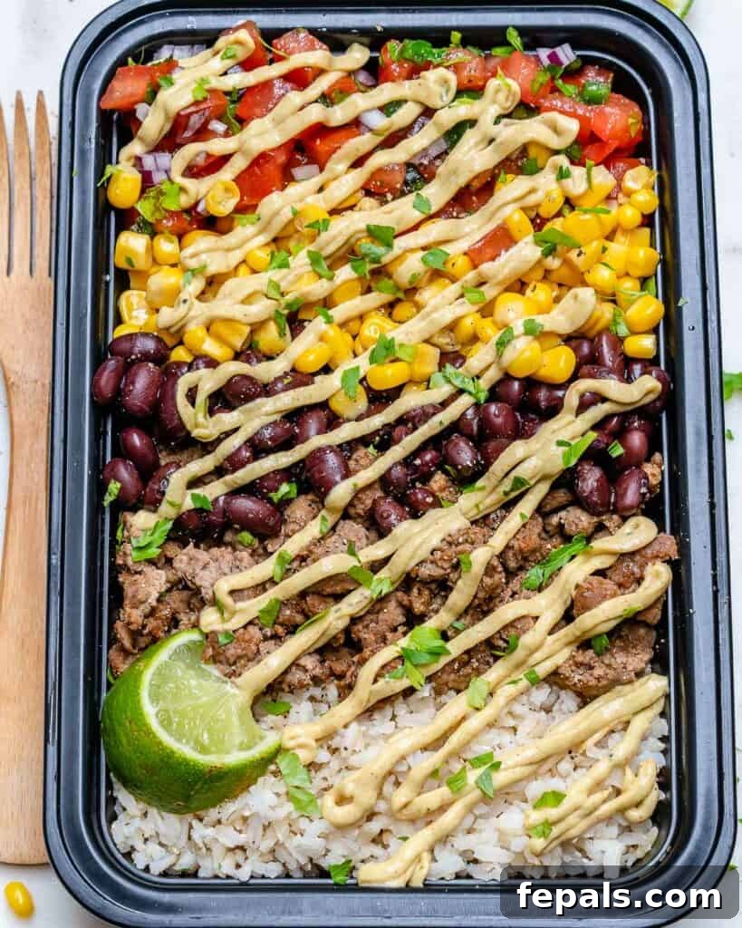 Beef Burrito Power Bowls 4 top view meal prep bowl with beef burrito. Made with ground beef, corn, beans, brown rice, and a drizzle of cream dressing