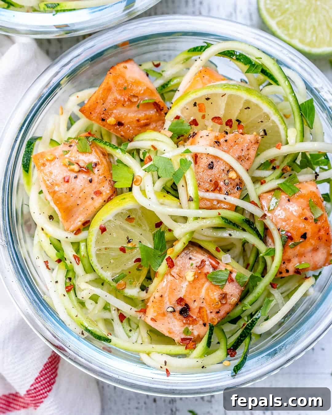 Zesty Chili Salmon Zoodles 4 Salmon and zucchini noodles artfully arranged with a lemon slice, highlighting the fresh ingredients in a glass container.