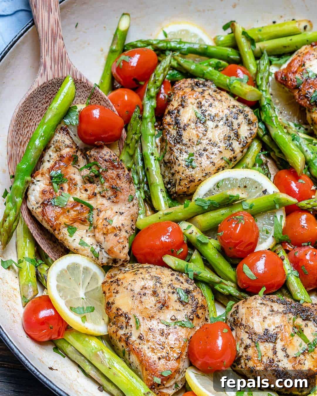 Seared Garlic Chicken Perfection 4 A cast iron skillet filled with perfectly cooked pan-seared chicken breast, bright green asparagus, and burst cherry tomatoes, steaming hot and ready to serve.