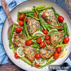 Seared chicken breast in a pan with asparagus and tomatoes.