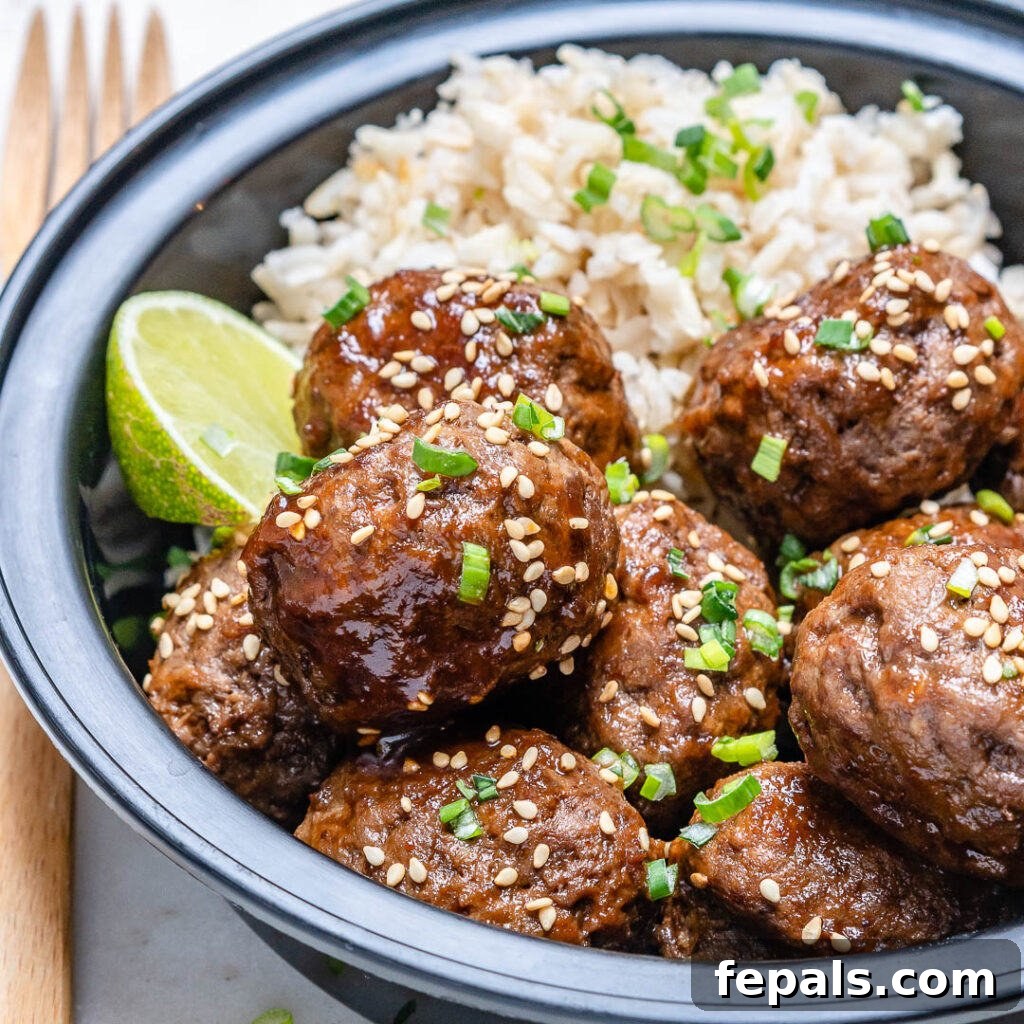 Honey Sriracha Glazed Asian Meatballs 3 side shot of Asian Honey Sriracha meatballs in a black meal prep bowl with brown rice topped with sesame seeds