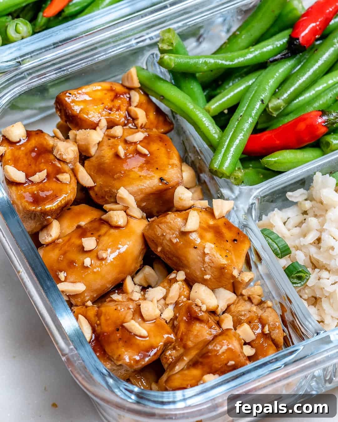 Overhead shot of sweet and spicy chicken with green beans and brown rice in a practical glass meal prep container.