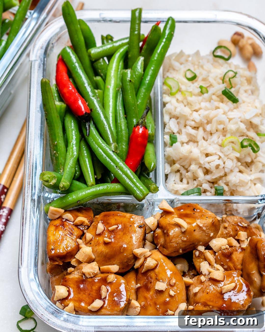 Kung Pao Chicken in a glass container with green beans and brown rice, presented as a complete and balanced meal.