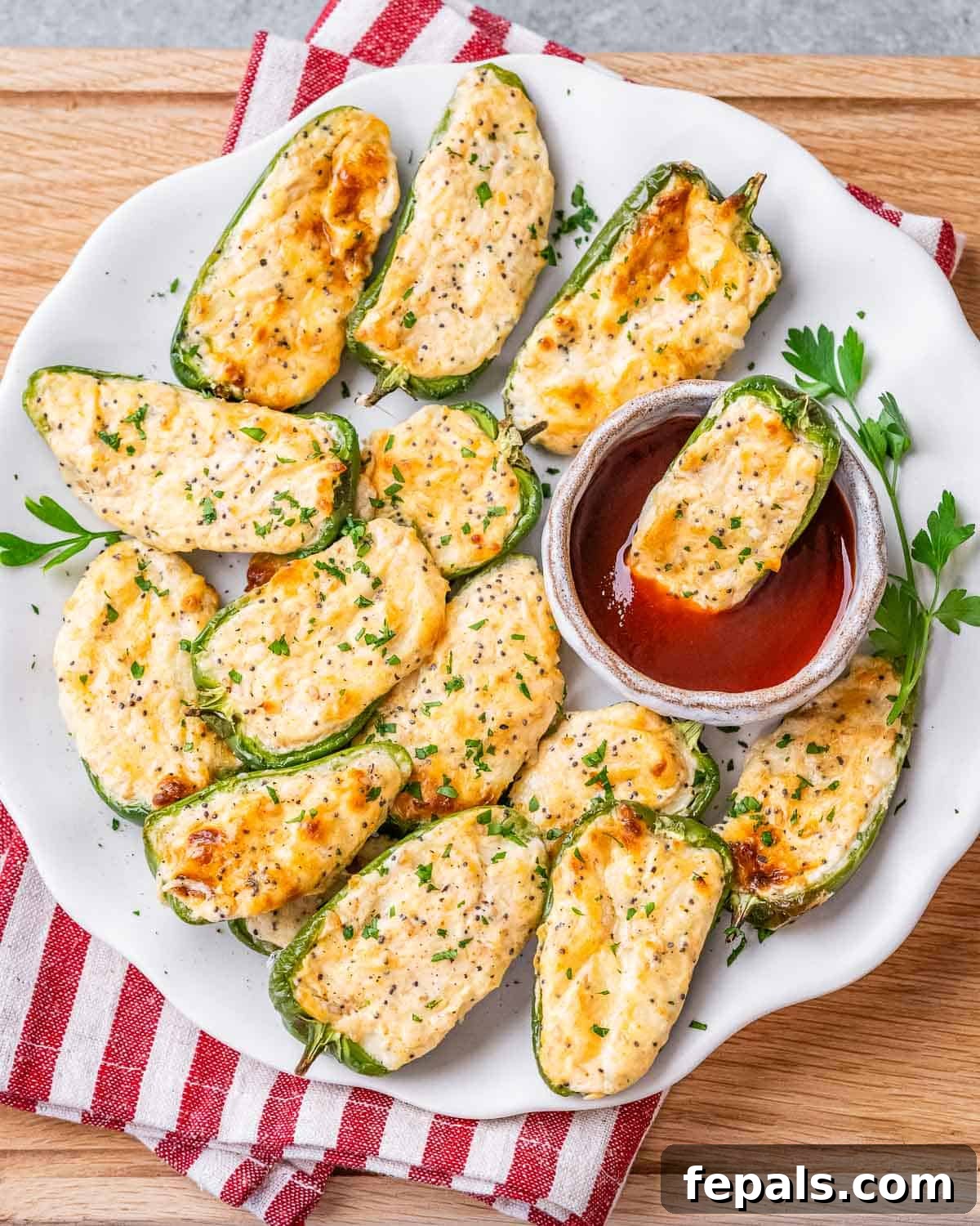 A plate of golden-brown baked jalapeno poppers with a small dipping sauce bowl on the side, ready to be enjoyed.
